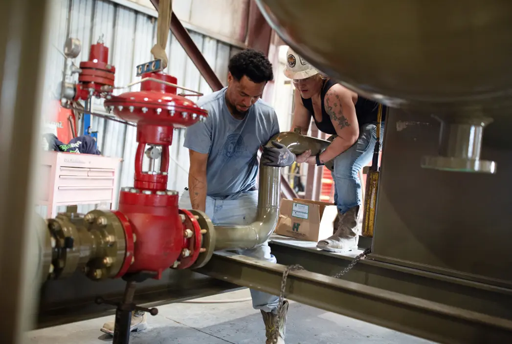 A man and a woman working together on a pipe.